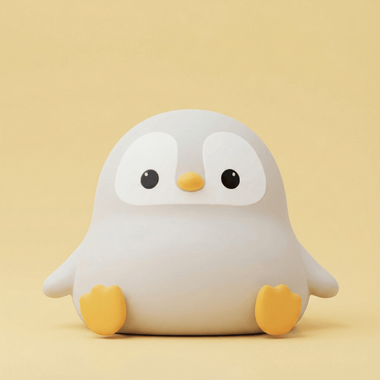 Cute light green squishy penguin silicone night light with a happy face and small limbs sitting on a solid pink background.